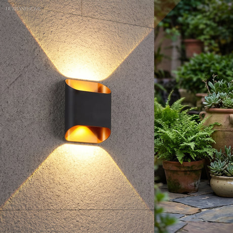 Black up down wall sconce lit on a textured render wall