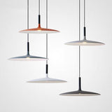 Four saucer pendants hung at different heights on a plain wall