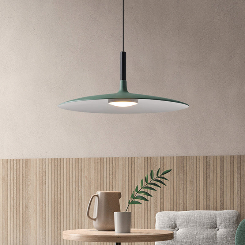 Green saucer pendant lit above a small round side table