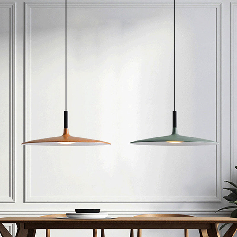 Orange and green saucer pendants lit above a timber table