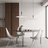 Two white saucer pendants above a dining table and wire chairs