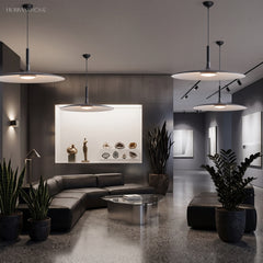 Two white saucer pendants lit in an open lounge with plants