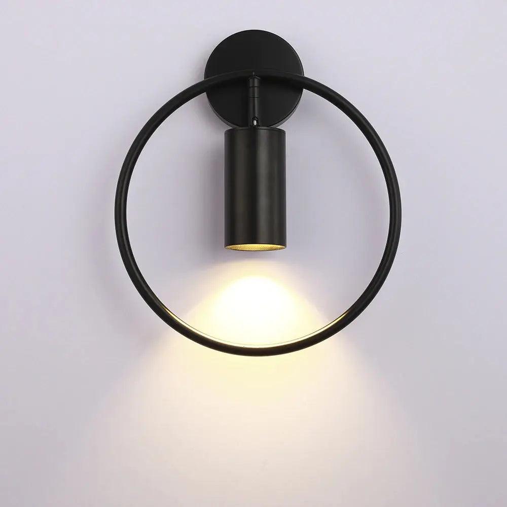 All black ring sconce with the cylinder spot casting light downward