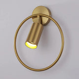 Brass cylinder tilted within its gold ring against a pale wall