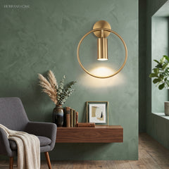Gold hoop sconce lit above a console table against a green wall