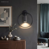 Black ring sconce lit on a dark wall above a wooden sideboard