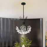 Black chandelier against a dark curtain beside a green potted plant