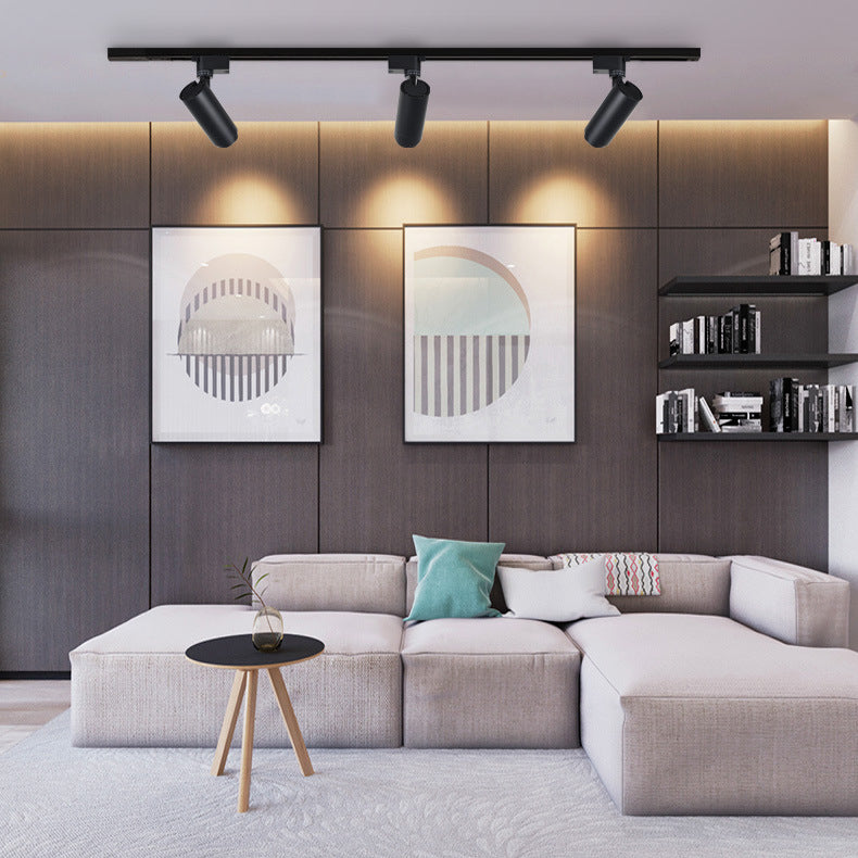 Three black spotlights lighting framed art above a living room sofa