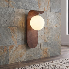 Wood tone wall sconce lit against a stone feature wall in hallway