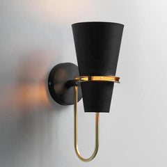 Black cone sconce lit warm against a plain white wall