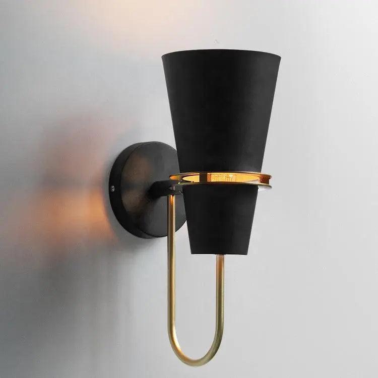 Black cone sconce lit warm and seen from a low angle