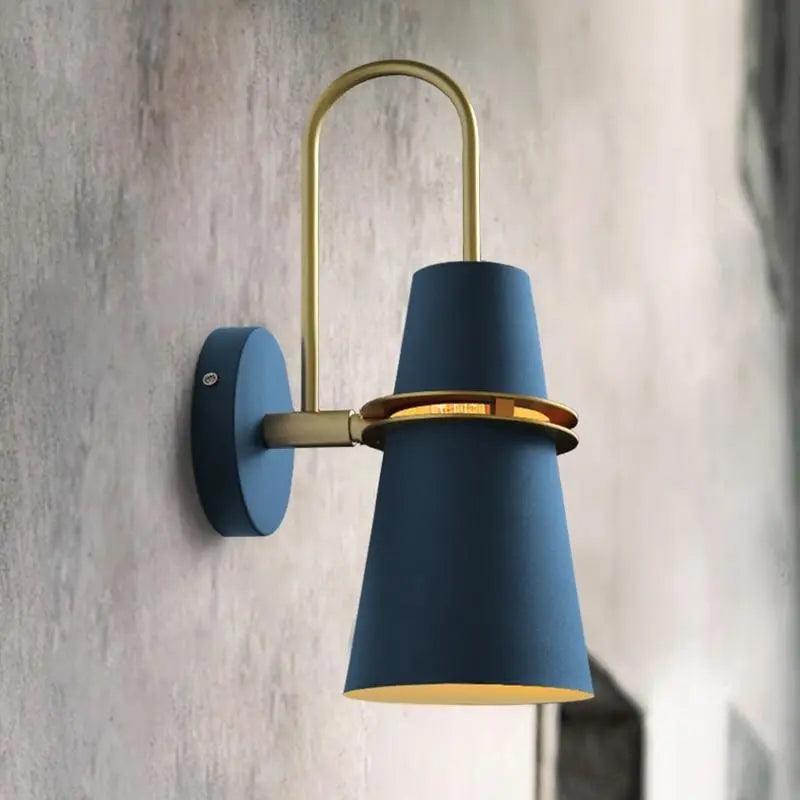 Blue cone shade sconce with a brass band on a plaster wall