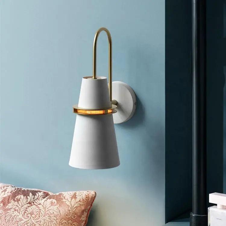 White cone sconce mounted on a soft blue wall above a cushion