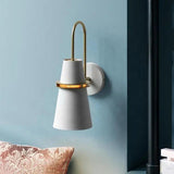 White cone sconce mounted on a soft blue wall above a cushion