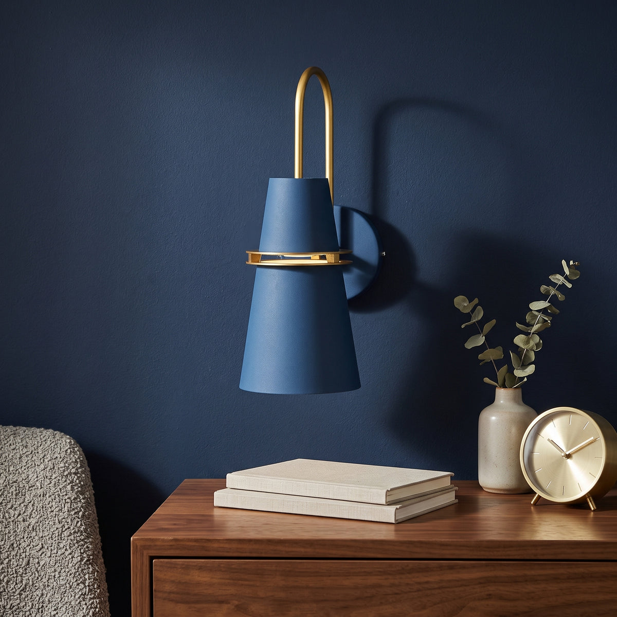 Blue cone shade wall sconce with a brass arm above a sideboard
