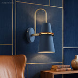 Blue cone sconce lit on a navy panelled wall by a leather chair
