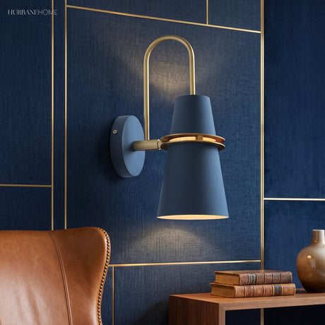 Blue cone sconce lit on a navy panelled wall by a leather chair