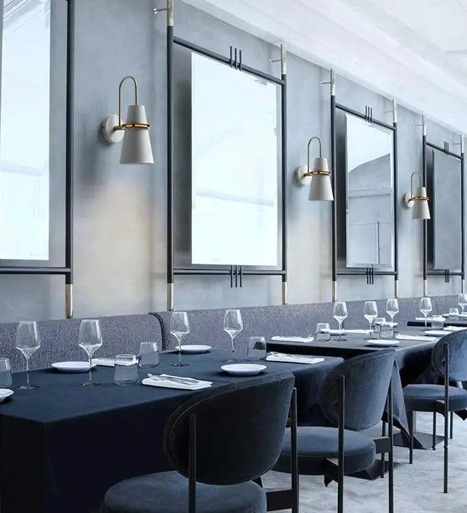 White cone sconces lit in a row between tall dining room windows