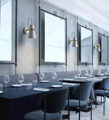 White cone sconces lit in a row between tall dining room windows