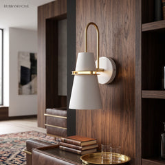 White cone sconce with a brass hook arm on a walnut wall