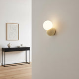 Wall sconce lit on a white hallway wall above a slim black console table