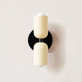Cream and cream cylinders mounted on a black round backplate