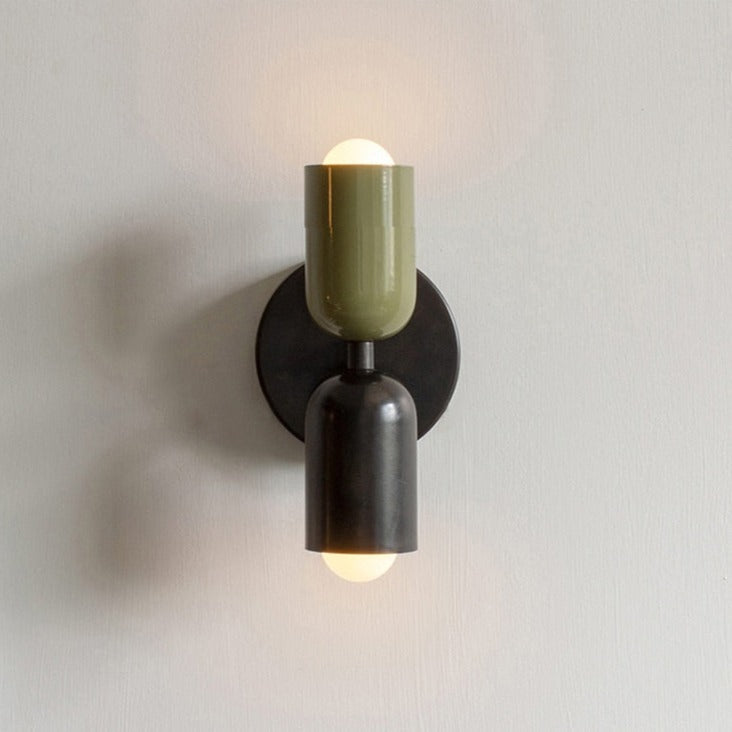 Olive and black sconce lit on a plain white wall