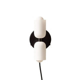 Two white cylinders on a black backplate with a trailing cord