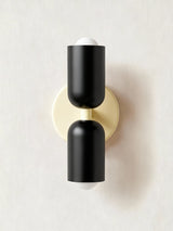 Two black cylinders on a cream backplate seen straight on