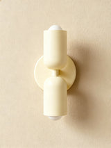 Cream cylinders on a cream backplate against a warm beige wall