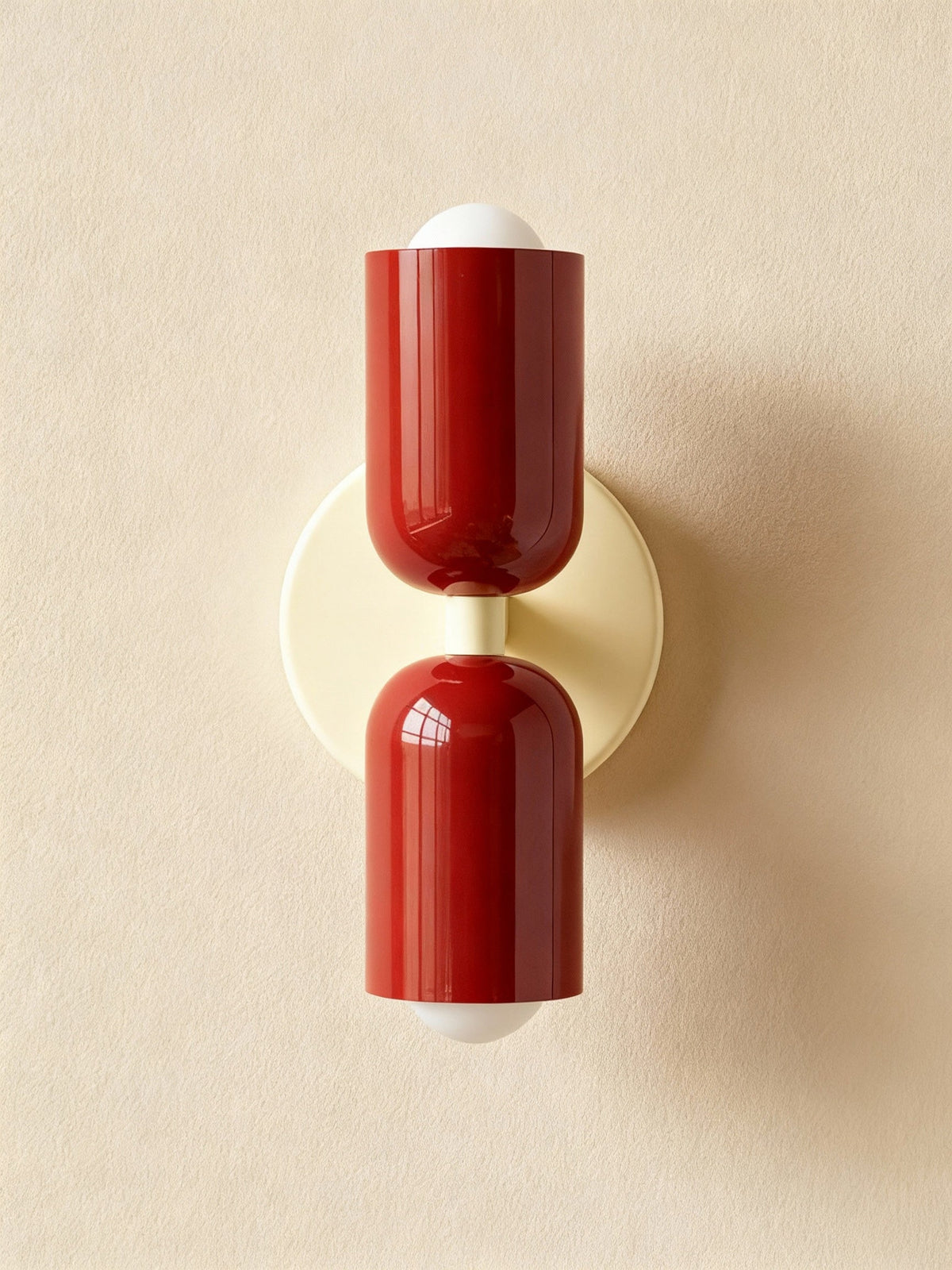 Two dark red cylinders on a cream backplate seen straight on