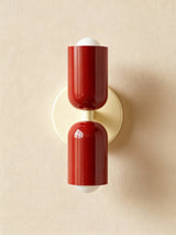 Dark red cylinders on a cream backplate against a beige wall