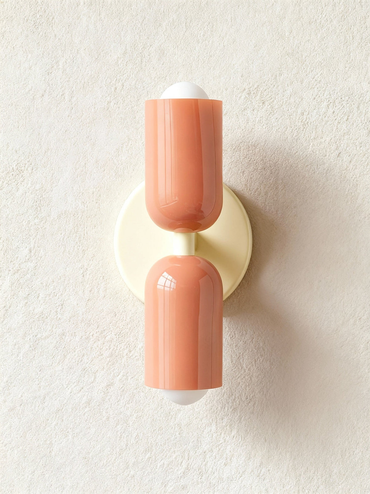 Terracotta cylinders on a cream backplate against textured plaster