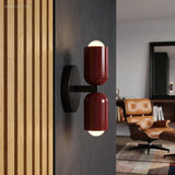 Two red cylinder sconces lit on a dark wall beside timber slats