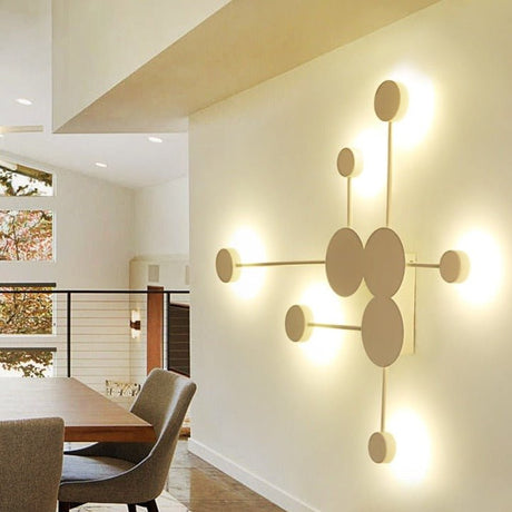 Gold six head wall sconce lit on a wall above a dining table