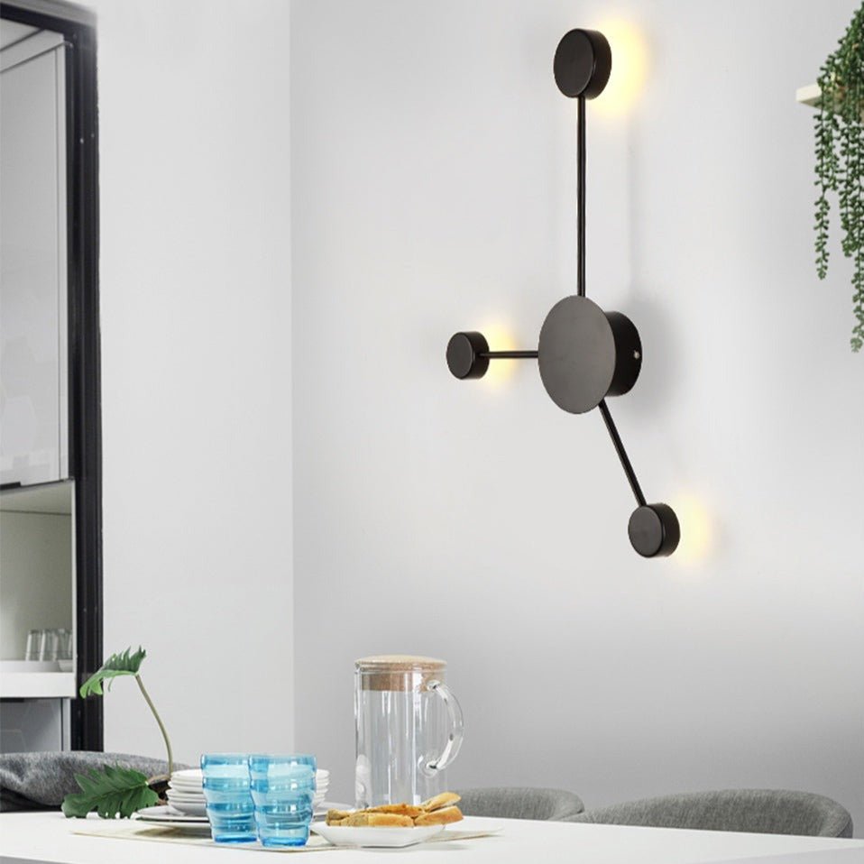 Dark grey three head wall sconce lit beside a dining table setting