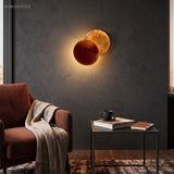 Copper toned disc sconce mounted above a living room armchair