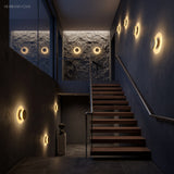 Row of moon disc sconces lighting a timber staircase wall