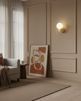 Wall sconce on a panelled beige wall in a living room with a leaning artwork
