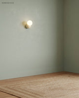 Single wall sconce mounted high on a plain sage green wall above a jute rug