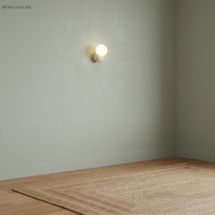 Single wall sconce mounted high on a plain sage green wall above a jute rug