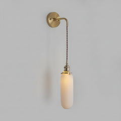 Slim capsule shade lit warm on a cord against a grey wall