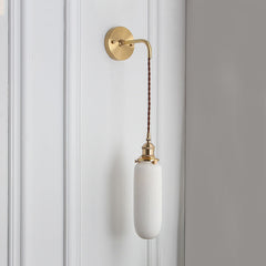 Slim capsule white shade hanging on a braided cord, shown unlit