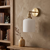 Ribbed drum shade on a brass arm against a warm plaster wall
