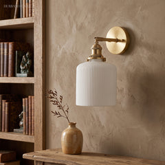 Ribbed drum shade on a brass arm against a warm plaster wall
