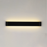 Black linear wall sconce lit on a plain white wall