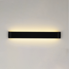 Black linear wall sconce lit on a plain white wall
