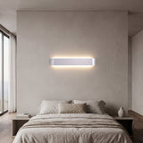 Silver linear LED wall sconce lit above a bed with pale bedding
