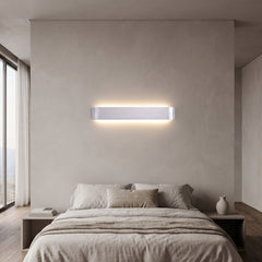 Silver linear LED wall sconce lit above a bed with pale bedding