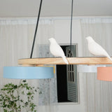 Wood round chandelier casting a warm glow from its integrated LED drum shades